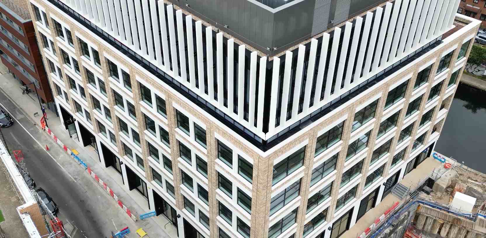 Apex Camden from a drone: white vertical fins above the brick-faced corner of an office building